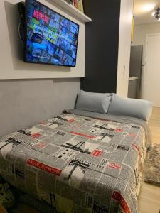 1 dormitorio con 1 cama y TV en la pared en (810 UA) Lindo Studio com estacionamento e internet !, en São Paulo