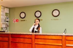 a woman talking on a cell phone behind a counter with clocks at Slavyanskaya Hotel in Vladivostok