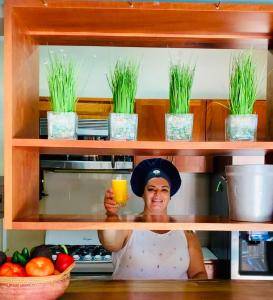 una mujer sosteniendo un vaso de jugo de naranja en una cocina en Ten North Tamarindo Beach Hotel en Tamarindo