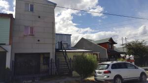 un coche blanco estacionado frente a una casa en Departamentos Buen Pasar en Ushuaia