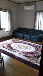 - un salon avec un canapé et un grand tapis dans l'établissement 町中ステイ 宗ハウス, à Nachikatsuura