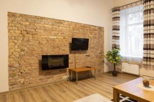 a living room with a brick wall with a tv at Sweet Apartments in Šiauliai