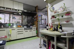 a kitchen with white cabinets and a table in it at HILDA INN in Kashiwa