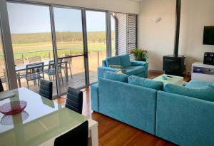 a living room with blue couches and a table and a balcony at Adina Vineyard in Lovedale