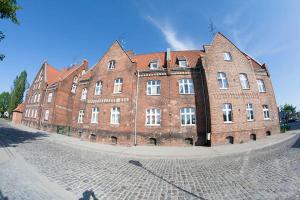 a large red brick building on a cobblestone street at Apartament Ołowianka- Danzig in Gdańsk