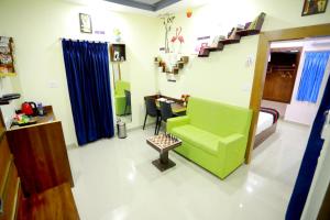 Habitación con cama, silla verde y mesa. en Base9 Cochin Airport Hotel en Nedumbassery