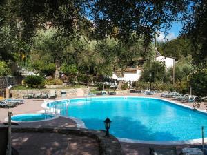 a large blue swimming pool with chairs and trees at Afrodite's Loft & Studios in Paleokastritsa