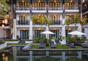 a hotel with chairs and umbrellas in front of a building at Aksara Heritage -SHA Extra Plus in Chiang Mai