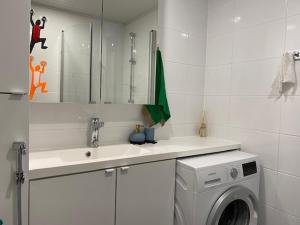 a white bathroom with a washing machine and a sink at QnQ studio apartment in Helsinki