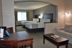 デュポンにあるFairBridge Inn & Suites DuPontのベッド2台とソファが備わるホテルルームです。