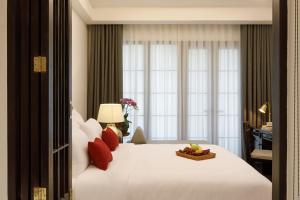 1 dormitorio con 1 cama blanca grande con almohadas rojas en Aksara Heritage -SHA Extra Plus en Chiang Mai