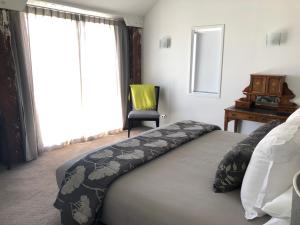 a bedroom with a bed and a chair and a window at Luxurious Loft Apartments in the heart of Ahuriri in Napier