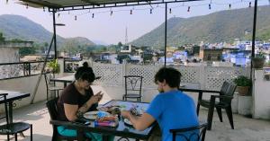 twee mensen aan tafel op een balkon eten bij Shivam Tourist Guest House in Būndi