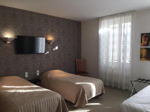 um quarto de hotel com duas camas e uma televisão na parede em Hôtel Restaurant La Boule d'Or em Barbezieux