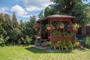 einen Gartenpavillon mit Blumen und Pflanzen darin in der Unterkunft Vogel Ági Vendégháza in Visegrád