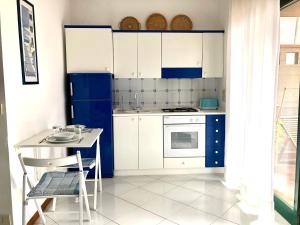 une cuisine avec des placards bleus et blancs et une table dans l'établissement Suite Gardenia, à Taormine