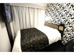 - une chambre avec un lit et une couverture noire et blanche dans l'établissement APA Hotel Toyohashi-Ekimae, à Toyohashi