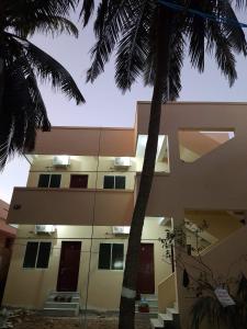 a building with a palm tree in front of it at Raghavi Tourist Home in Kanyakumari