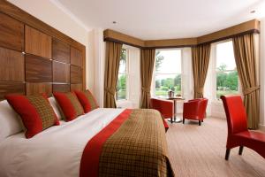 a hotel room with a bed and a desk and windows at The Glenmoriston Townhouse Hotel in Inverness