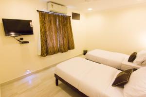 a room with two beds and a flat screen tv at Cloud Nine Serviced Apartments in Chennai