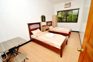 a bedroom with two beds and a table and a window at Tatay Seseng's Apartment in Panglao Island