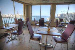 a restaurant with tables and chairs and large windows at Carlton Hotel in Sliema