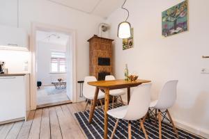 #1 AUGSBURG Altstadtjuwel في اوغسبورغ: مطبخ وغرفة طعام مع طاولة خشبية وكراسي بيضاء