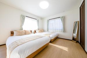 2 Betten in einem weißen Zimmer mit Fenstern in der Unterkunft Fuji Viewest Villa RAKUWA in Fujikawaguchiko