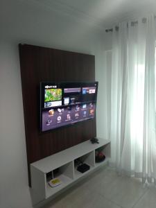 TV de pantalla plana en la pared de la sala de estar. en Atalanta 201A, en Bombinhas