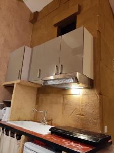 una cocina con armarios blancos y una capucha sobre un fregadero en Gites Climatisés Piscine Chauffée La Balancelle en Saint-Rémy-de-Provence