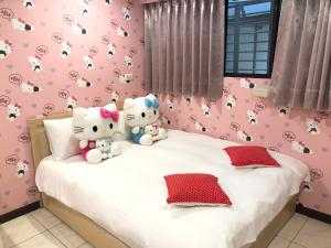 two hello kitty stuffed animals sitting on a bed at Jacky's House Ximen in Taipei