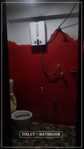 a bathroom with a toilet and a red wall at Planet Nomad Hostel in Kathmandu