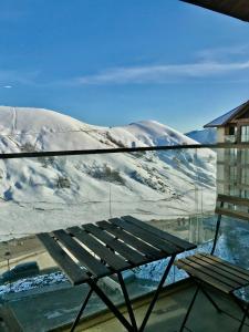 a bench on a balcony with a snow covered mountain at New Gudauri Lofts by Gudauri Travel in Gudauri