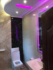 a bathroom with a toilet and a purple light at Trio Villa with coverable private pool in compound near Mall of Egypt in Sheikh Zayed