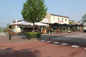 a building with tables and umbrellas on a city street at B&B - Eetcafe - Riekelt in Gronsveld