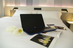 a laptop computer sitting on top of a bed with a book at Hotel NERU con Encanto in León
