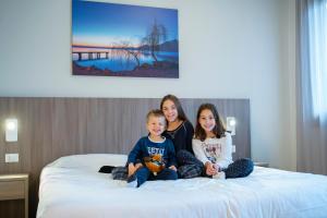zwei Frauen und ein Kind auf einem Bett in der Unterkunft Le Torri Del Garda FamilySPA Resort in Torri del Benaco