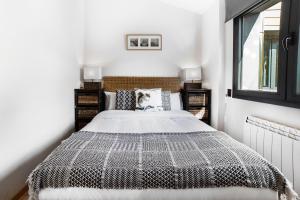 Schlafzimmer mit einem Bett mit einer schwarzen und weißen Bettdecke in der Unterkunft Apartaments El Floc in El Tarter