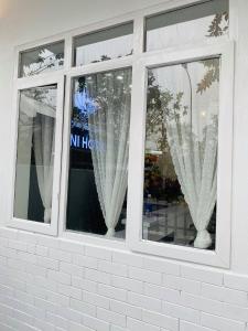2 fenêtres avec des rideaux blancs dans un magasin dans l'établissement Hotel Mini, à Phú Thọ