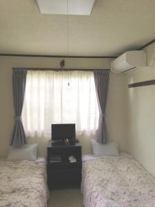 a bedroom with two beds and a window with a tv at Pension Rapan in Katashina