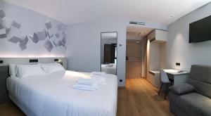 a hotel room with a white bed and a desk at Hotel NERU con Encanto in León