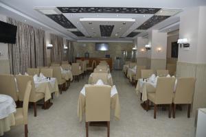 uma sala de jantar com mesas e cadeiras brancas em HOTEL AMSTERDAM em Rouiba