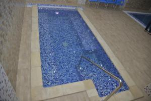 una gran piscina con azulejos azules en el suelo en HOTEL AMSTERDAM, en Rouiba