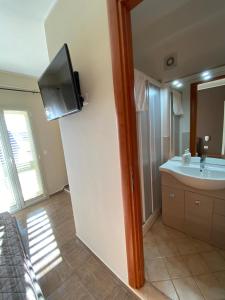 a bathroom with a sink and a tv on the wall at Nick & Santo's Holiday Homes B&B in Giardini Naxos