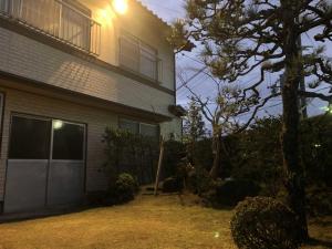 una casa con un árbol delante de ella en GINGAYA, en Iwataki