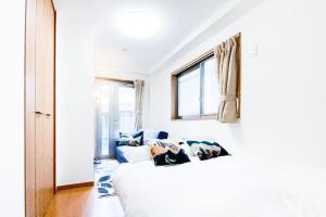 - une chambre avec un lit blanc et un canapé bleu dans l'établissement Yahiro 4-chome House 1F, à Tokyo
