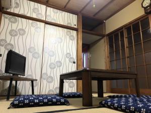 a room with a table and a tv and a wall at GINGAYA in Iwataki