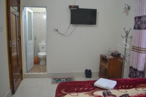 a bathroom with a bed and a television on the wall at Phong Nha Homestay in Phong Nha
