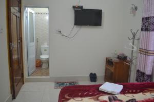 baño con cama y TV en la pared en Phong Nha Homestay, en Phong Nha