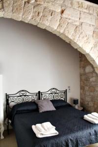 a bedroom with a black bed with a stone wall at Il Mulino di Amleto - Bed and Breakfast letterario in Molfetta